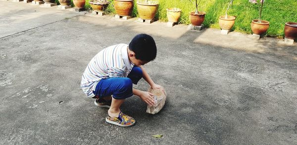 Full length of boy petting rabbit on road