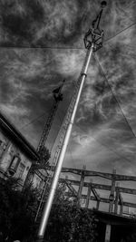 Low angle view of crane against cloudy sky