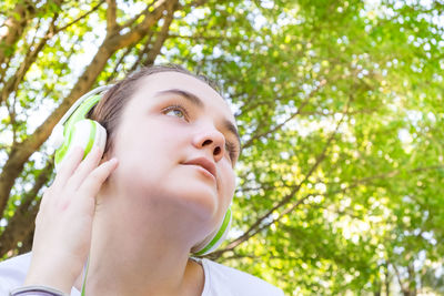 Portrait of young woman looking away against trees