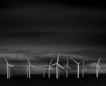 Wind turbines on field against sky