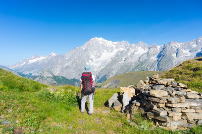 Rear view of backpack hiker standing against mountains in winter