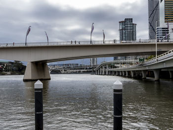 Bridge over river in city against sky