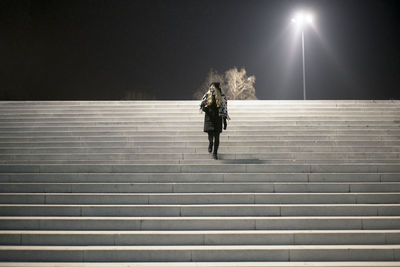 Rear view of woman on staircase at night