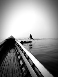 Fisherman fishing in inle lake against clear sky