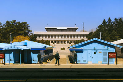 People in front of built structure against blue sky