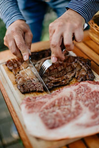 Midsection of person cutting meat