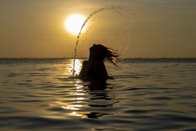 Silhouette woman standing by sea against sky during sunset