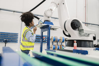 Engineer analyzing robotic arm machine in factory