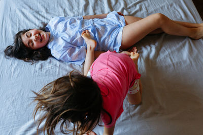 One smiling girl lying on the bed and other child jumping over