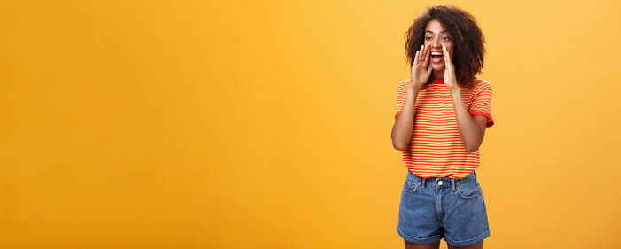 Rear view of woman standing against yellow background