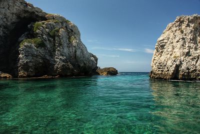 Rock formation in sea against sky