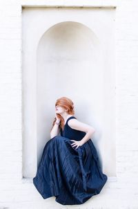 Woman looking away while sitting against wall