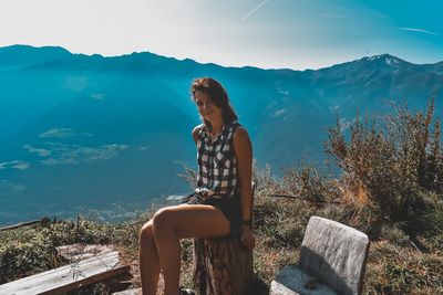 Woman sitting against mountain range against sky