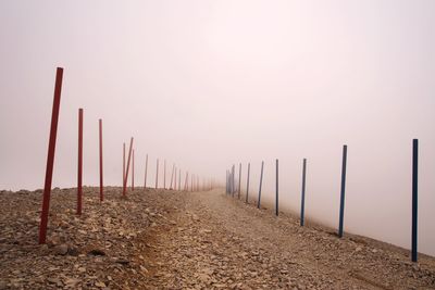 Wooden posts on field against foggy sky