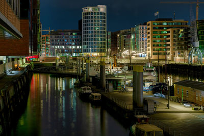 Canal amidst illuminated buildings in city at night