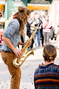 Saxophone player on his back playing next to a guitarist on the street