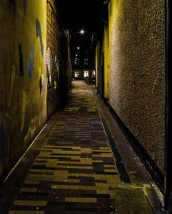 Narrow alley amidst buildings in city at night