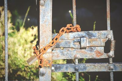 Close-up of rusty metal tied up on fence