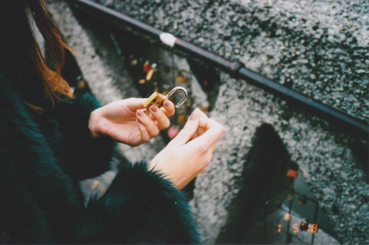 one person, holding, real people, hand, human hand, lifestyles, leisure activity, human body part, high angle view, day, outdoors, bad habit, cigarette, women, nature, rail transportation, focus on foreground, finger