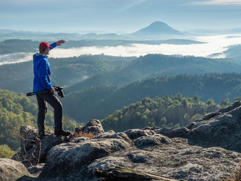 Man photographer looking with camera in hands for subject bellow mountain path. discovery travel