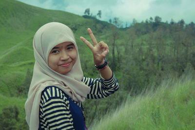 Portrait of smiling girl gesturing while standing on grass