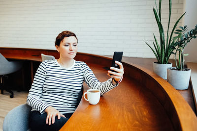 Portrait of young woman using mobile phone while sitting at home