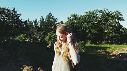 Happy woman against trees on sunny day