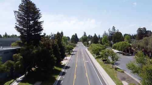 Aerial drone view of road amidst trees against sky