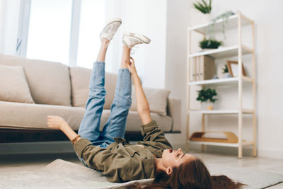 Side view of woman using mobile phone while sitting on bed at home