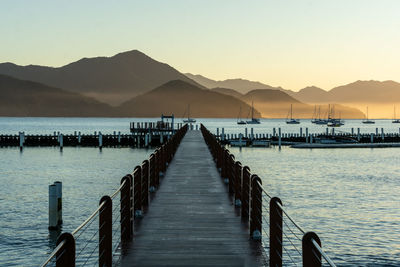 Pier over sea against sky during sunset