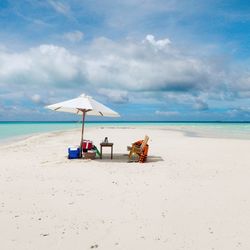 Lounge chairs on beach against sky