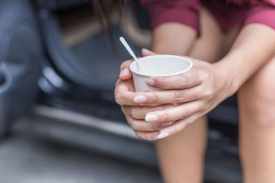 Midsection of woman holding drink while sitting in car