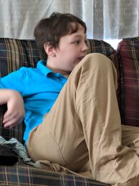 Boy sitting on sofa at home