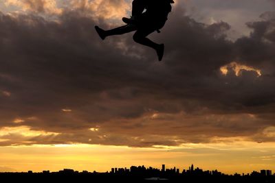 Silhouette of flying against dramatic sky during sunset
