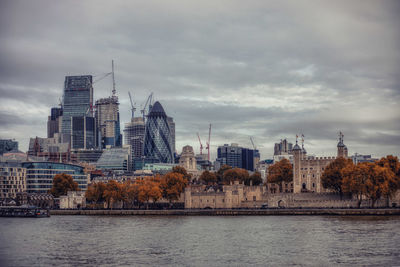 City at waterfront against cloudy sky