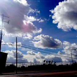 Low angle view of electricity pylon against cloudy sky