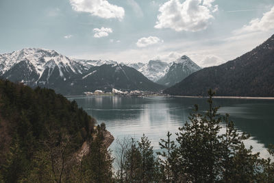 Scenic view of lake by snowcapped mountains against sky