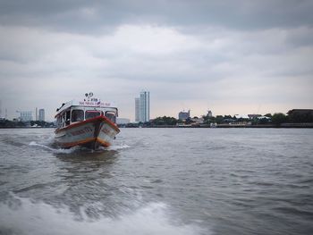 Ship sailing in sea against sky in city