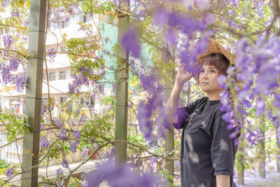 Low angle view of boy standing on flowering tree