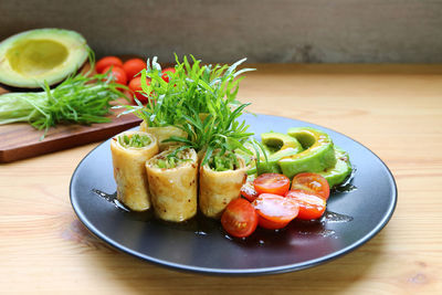 Mouthwatering egg rolls with fresh water spinach microgreens, avocado and tomato salad