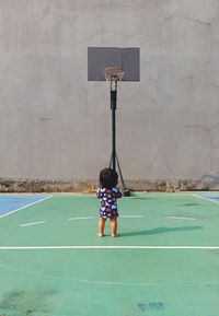 Toddler looking at basketball hoop in court