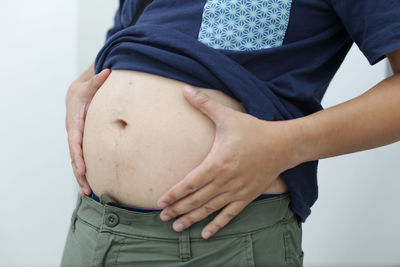 Midsection of woman touching hair over white background