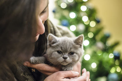 Close-up of woman holding kitten against christmas tree