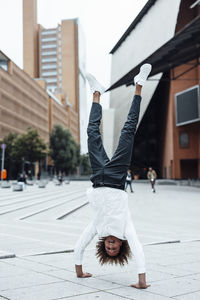 Happy businessman doing handstand on square