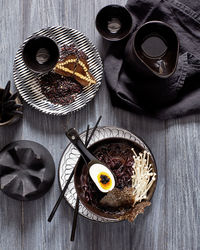 Still life of ramen noodles in bowl, egg, textured props