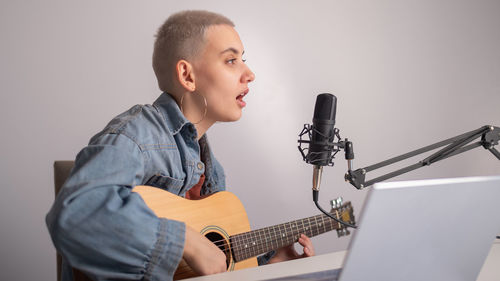 Full length of man playing guitar against wall