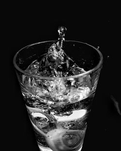 Close-up of water splashing in glass against black background