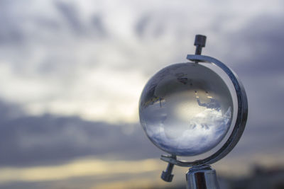 Close-up of glass globe against cloudy sky