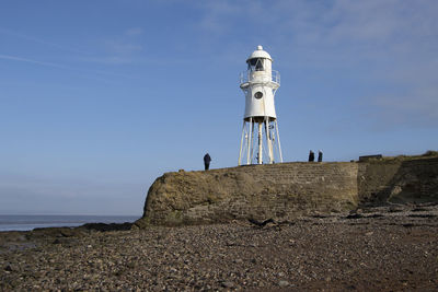 Lighthouse by sea against sky