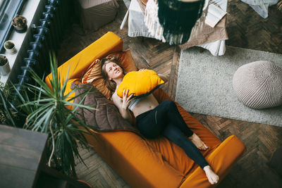 Top view of young woman lying on sofa at home. girl resting lying on the couch and hugging a pillow